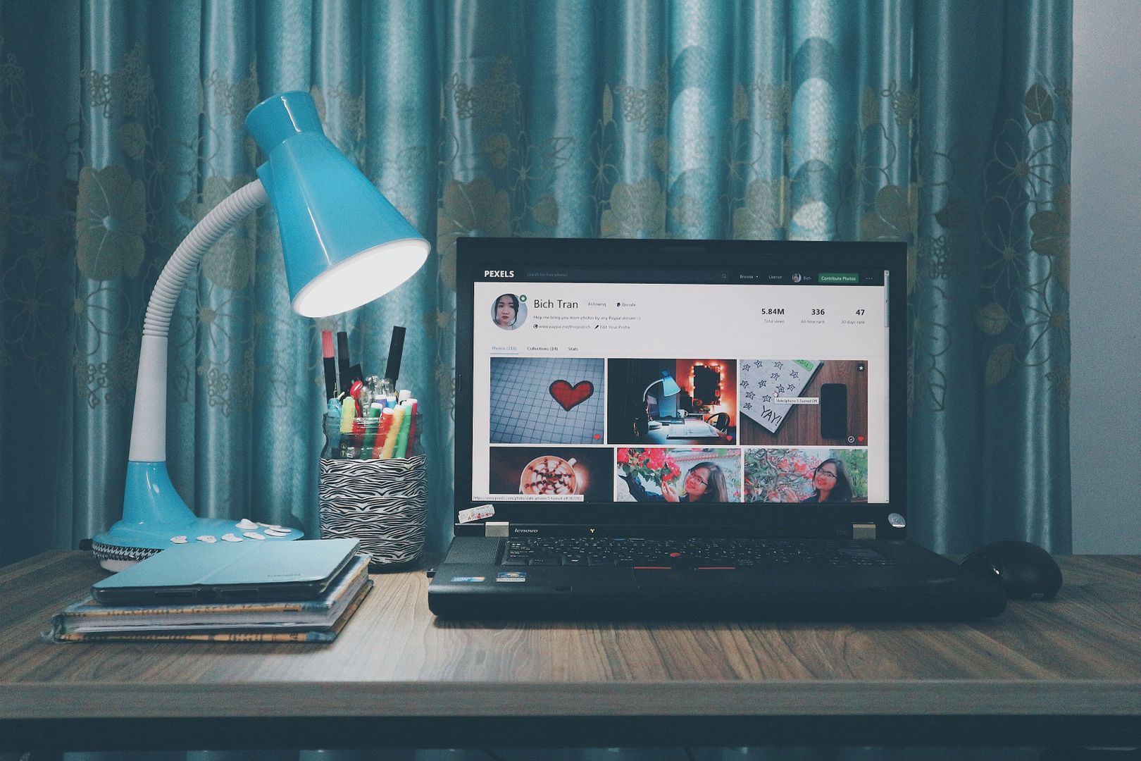 A modern home office desk setup featuring a laptop, blue lamp, and stationery in a well-lit interior.